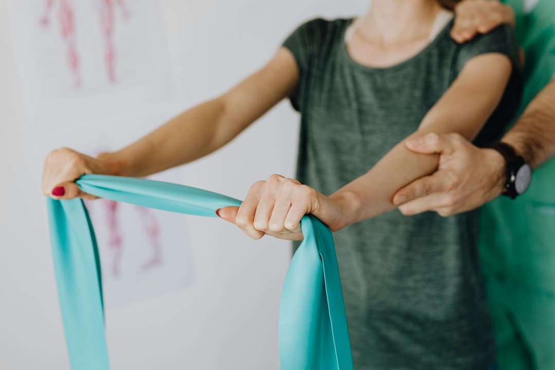 Eine Frau, welche mit Hilfe eines Trainers Übungen macht. Die Übung dient der besseren Rückenmuskulatur und dadurch der Körperhaltung.